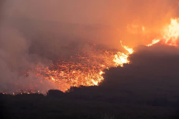 Large wildfires spreading across Saddleworth Moor and towards residential areas.