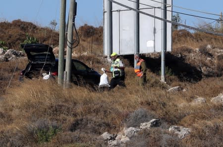 An Israeli soldier and a member of Zaka Rescue and Recovery team work near the scene where the Israeli military said an Israeli soldier was found stabbed to death near a Jewish settlement in the Israeli-occupied West Bank