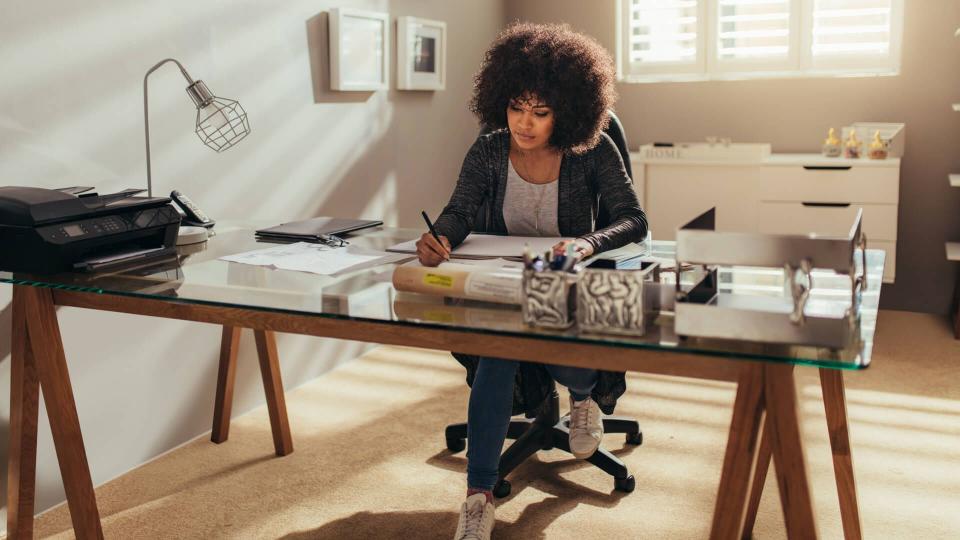 African woman working on new building plans while sitting at her desk.