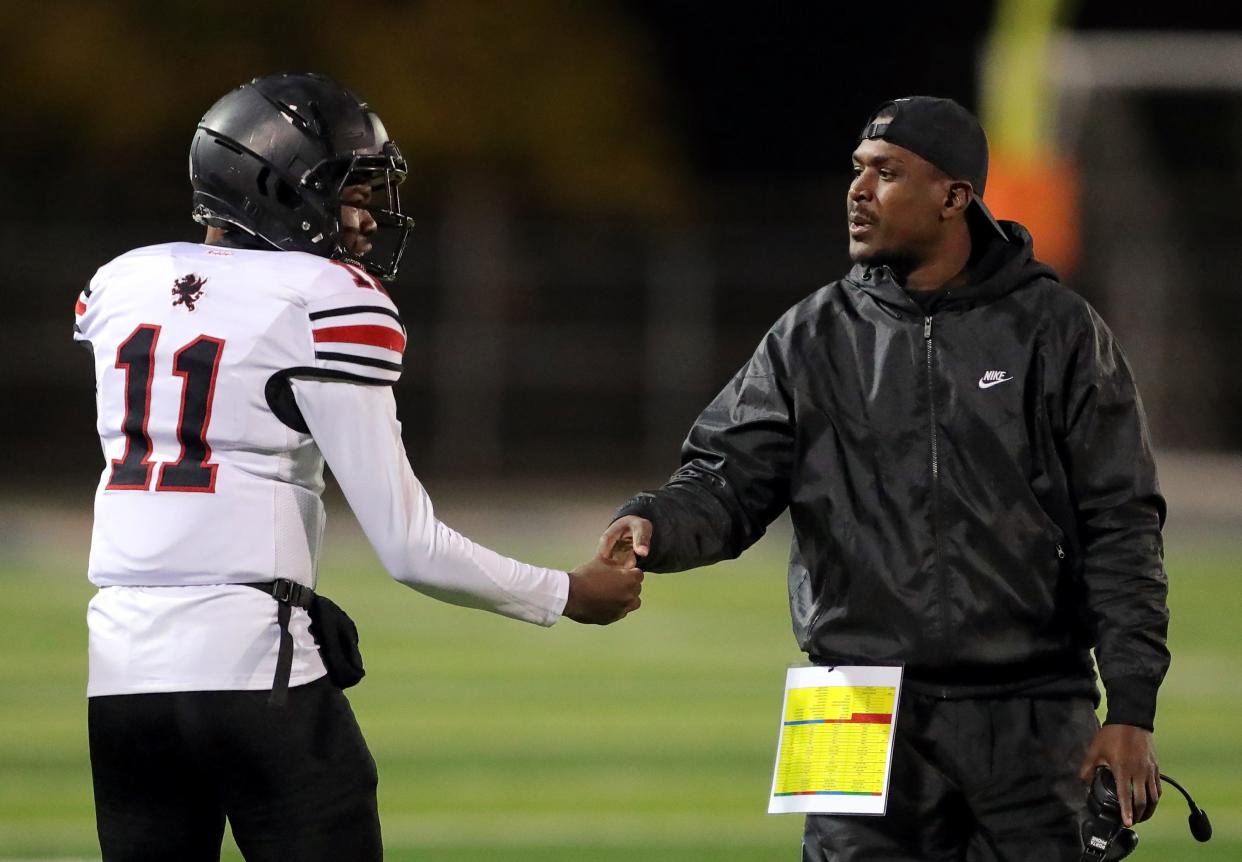 Buchtel football coach Bryan Williams, right, shakes hands with quarterback Stevie Diamond after his first-half touchdown run against Firestone, Friday, Oct. 21, 2022.