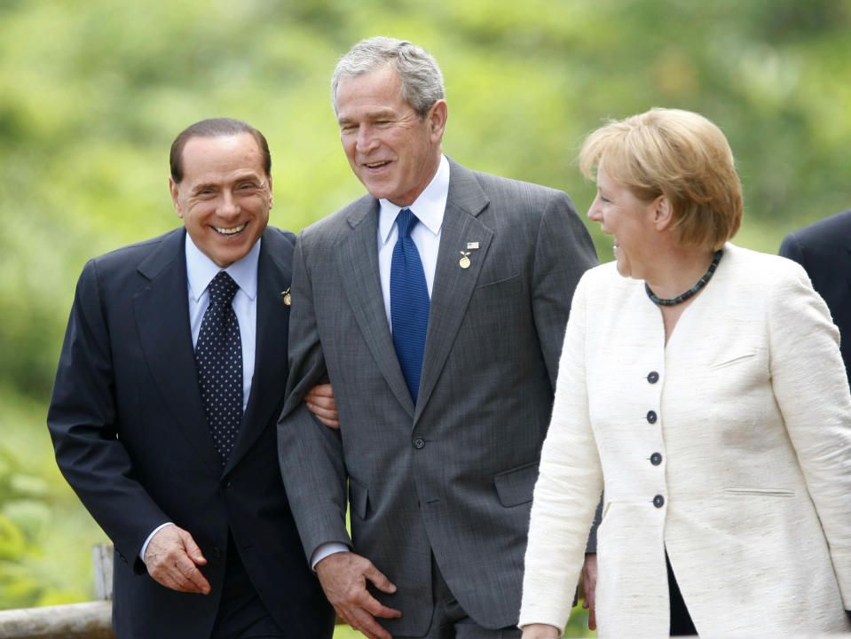 FILE - From left to right, Italian Prime Minister Silvio Berlusconi, holds on to the arm of U.S. President George W. Bush, as German Chancellor Angela Merkel, looks on before posing for the official photo at the G8 summit, July 8, 2008 in the lakeside resort of Toyako on Japan northern main island of Hokkaido. Berlusconi, the boastful billionaire media mogul who was Italy's longest-serving premier despite scandals over his sex-fueled parties and allegations of corruption, died, according to Italian media. He was 86. (AP Photo/Pablo Martinez Monsivais, File)