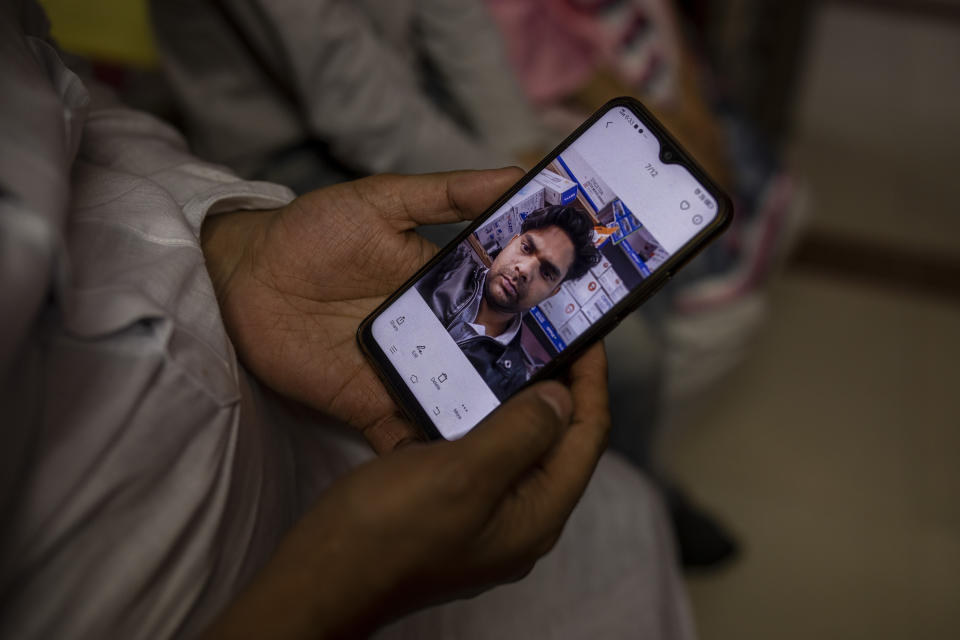 Haroon holds a mobile phone with a photograph of his 32 year-old brother who was shot and killed by his Hindu neighbors during the February 2020 communal riots, inside his home in North Ghonda, one of the worst riot affected neighborhood, in New Delhi, India, Friday, Feb. 19, 2021. As the first anniversary of bloody communal riots that convulsed the Indian capital approaches, Muslim victims are still shaken and struggling to make sense of their struggle to seek justice. (AP Photo/Altaf Qadri)