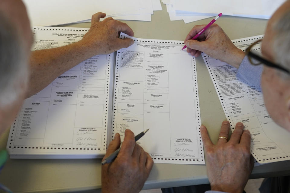 FILE - Democrat and Franklin County Commissioner Bob Ziobrowski, right, and Republican and member of the Franklin County election board Jerry Warnement, left, work together to review and duplicate damaged absentee and mail-in ballots that would not go through the electronic ballot scanner the morning after the Pennsylvania primary election at the Franklin County offices in Chambersburg, Pa., May 18, 2022. (AP Photo/ Carolyn Kaster, File)