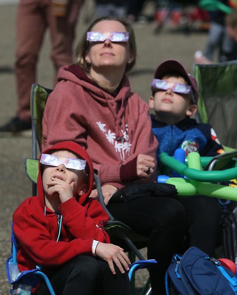 Lidia Kasiak of Fairfax, Virginia, watches the eclipse with her sons, Adam, 6 and Phillip, 10 at the Akron 24 Eclipse With Us party in Akron on Monday. The family drove to Akron to be in the path of totality.