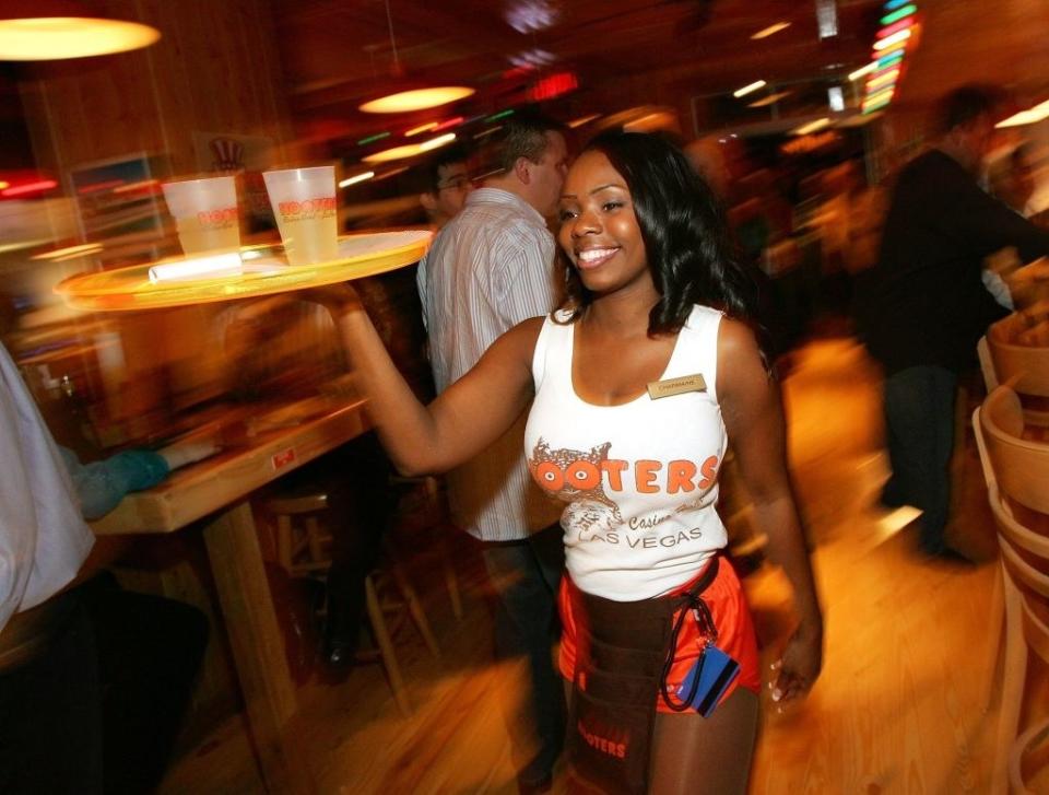 A Hooters waitress holding a tray of drinks.