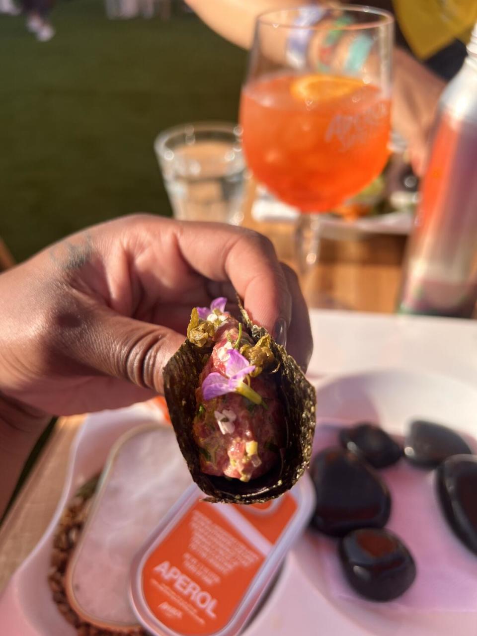 A hand holds a carpaccio hand roll