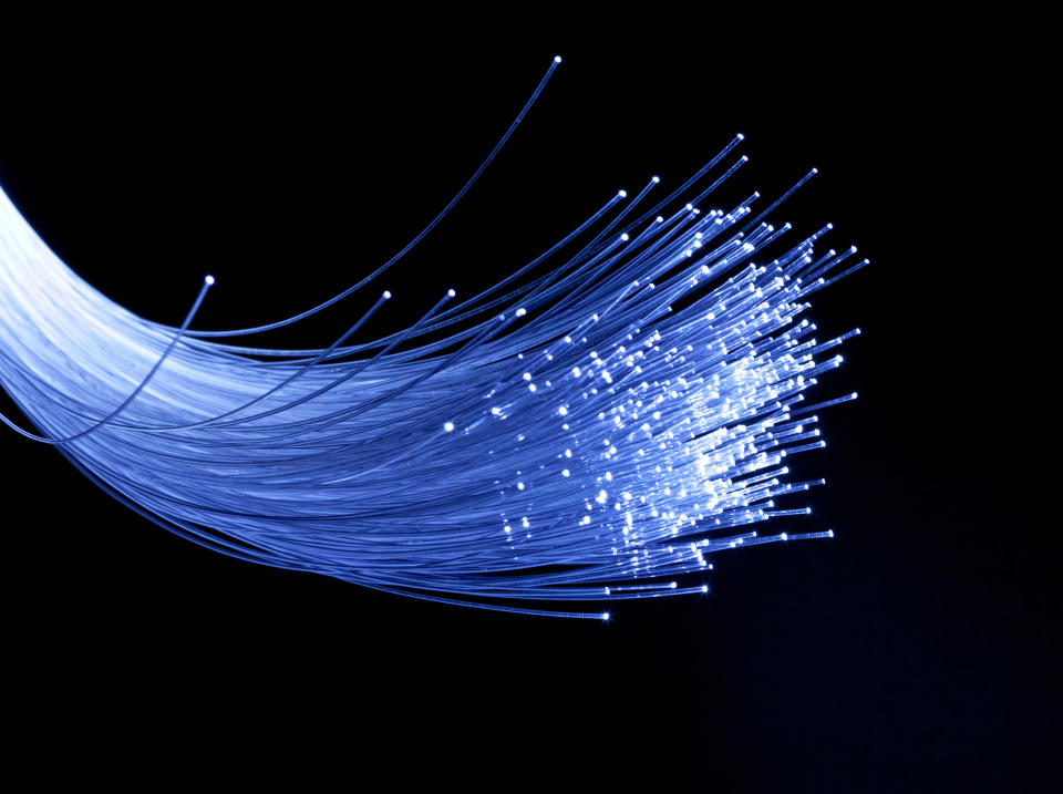 A bundle of fiber-optic wires lit up in white against a black background.