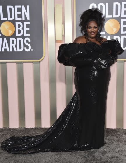 Nicole Byer in a black dress on the gray carpet at the Golden Globe Awards