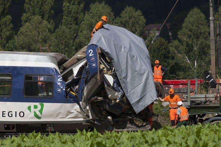 Workers on the site of a train accident in Granges-Pres-Marnand, western Switzerland on July 30, 2013, the day after the crash. Signal-jumping is thought to have caused the head-on train collision that killed at least one person, national rail company CFF said Tuesday