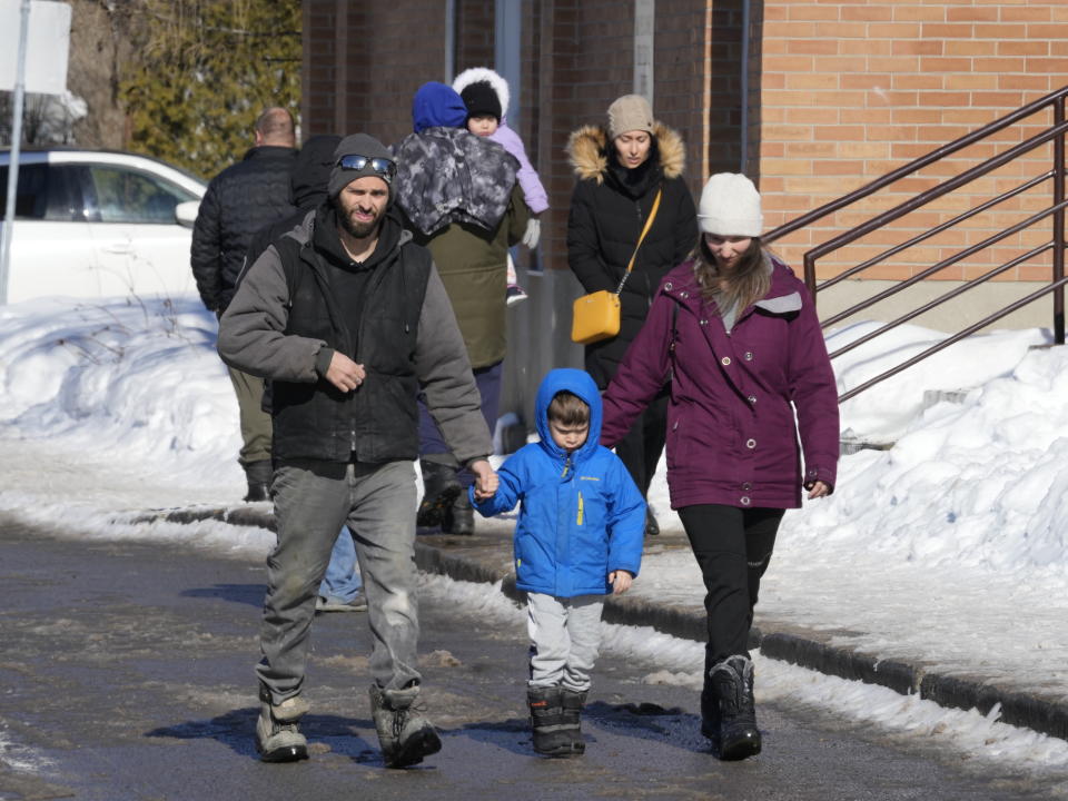 A couple escorts a child from a daycare centre after a city bus crashed into the facility in Laval, Quebec, Wednesday, Feb.8, 2023. At least eight people including several children have been sent urgently to hospital after a city bus crashed into a daycare north of Montreal Wednesday morning, emergency officials say. (Ryan Remiorz/The Canadian Press via AP)
