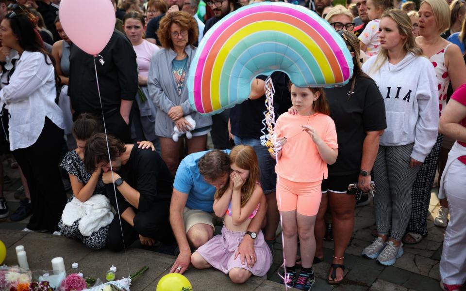 People gather to pay their respects during a vigil in central Southport