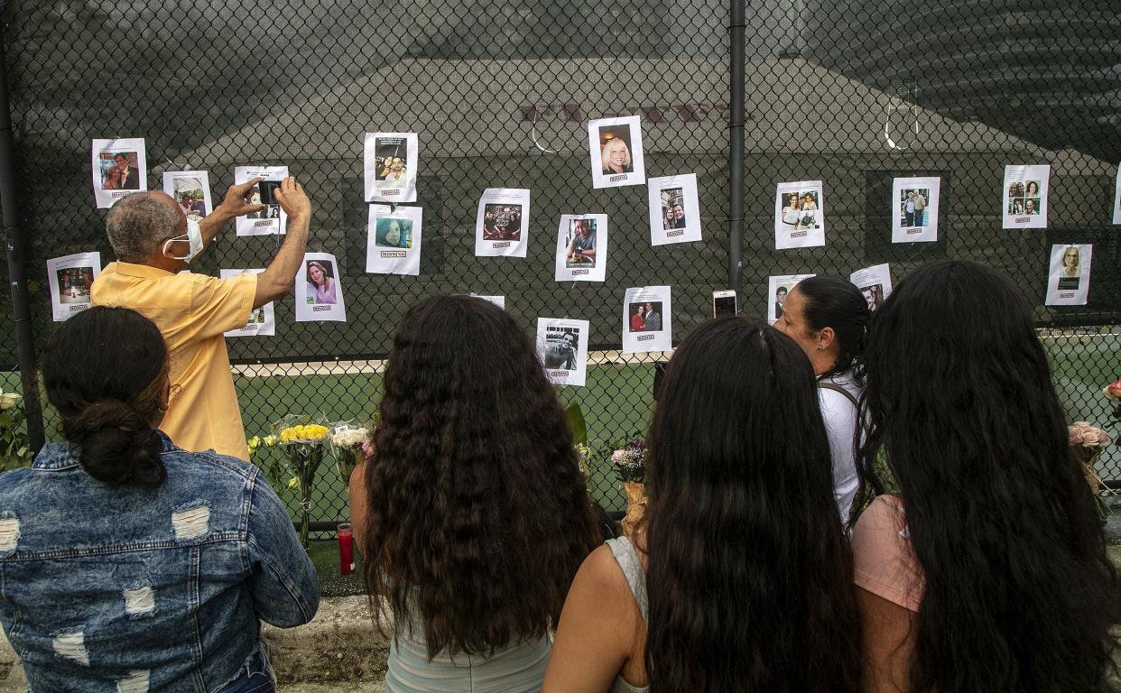 Photos of missing people are posted on a fence near the site of the Champlain Towers South Condo on Friday, June 25, 2021, in Surfside, Fla.