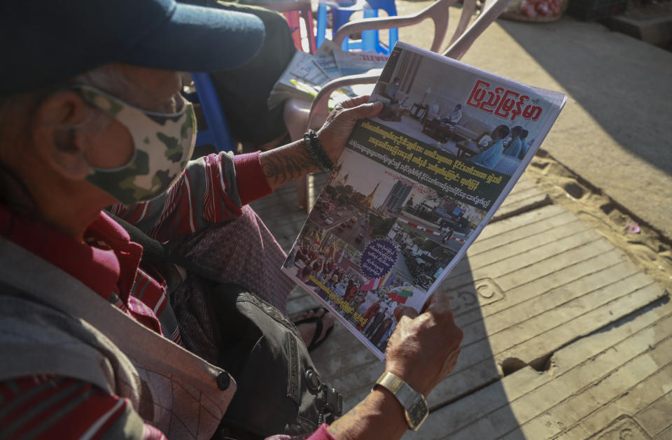 FILE - In this Feb. 2, 2021, file photo, a man looks at a newspaper, which reports "1 year of State of Emergency and Acting President transferred Power to Military Chief" on the front page, in Yangon, Myanmar. Myanmar’s military-controlled government is seeking to suppressing media coverage of protests against their seizure of power as journalists and ordinary citizens strive to keep people inside and outside of the country informed about what is happening. (AP Photo/File)