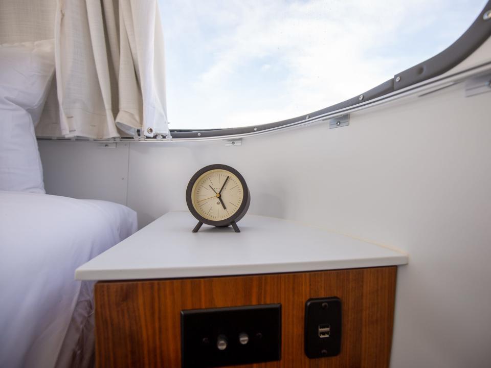 Autocamp Joshua Tree's Airsteram trailer with a clock next to a bed.