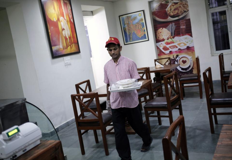 An inmate carries a tray after serving food inside a restaurant run by the Tihar Jail authorities on Jail Road in west Delhi July 21, 2014. "Tihar Food Court" in west Delhi, a rehabilitation effort kicked off by the Tihar prison, opened in the first week of July on an "experimental basis" while awaiting formal clearances. It is sited half a km (0.6 mile) away from prisoners' dormitories. With a spacious interior lined with wooden tables and walls adorned with paintings done by prisoners, the 50-seat restaurant has been praised for the polite behaviour of its employees, who were trained by a prestigious nearby hotel management school. Picture taken July 21, 2014. REUTERS/Anindito Mukherjee (INDIA - Tags: CRIME LAW FOOD SOCIETY)