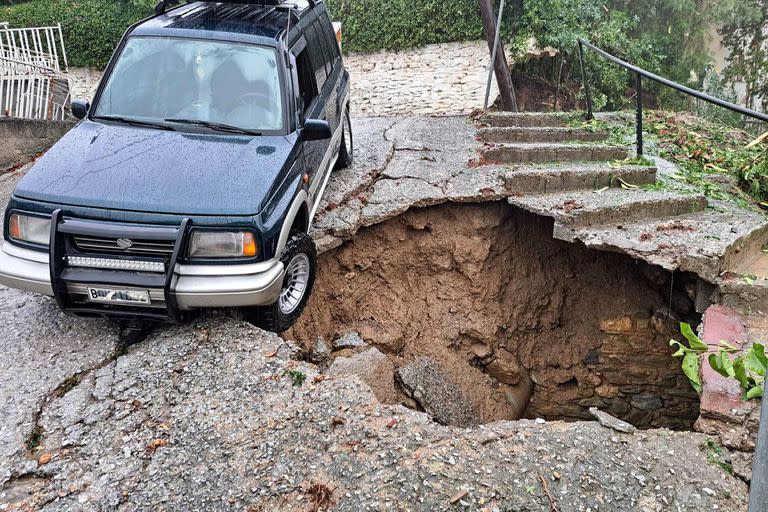 Una foto muestra un automóvil cerca de un agujero en una calle durante una inundación en Volos el 5 de septiembre de 2023