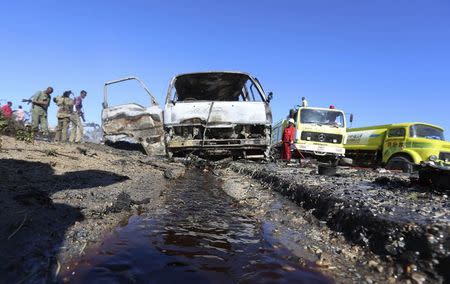 A fireman (R) extinguishes fire from the wreckage of a van after a suicide car bomb explosion targeting peacekeeping troops in a convoy outside the capital Mogadishu September 8, 2014. REUTERS/Feisal Omar