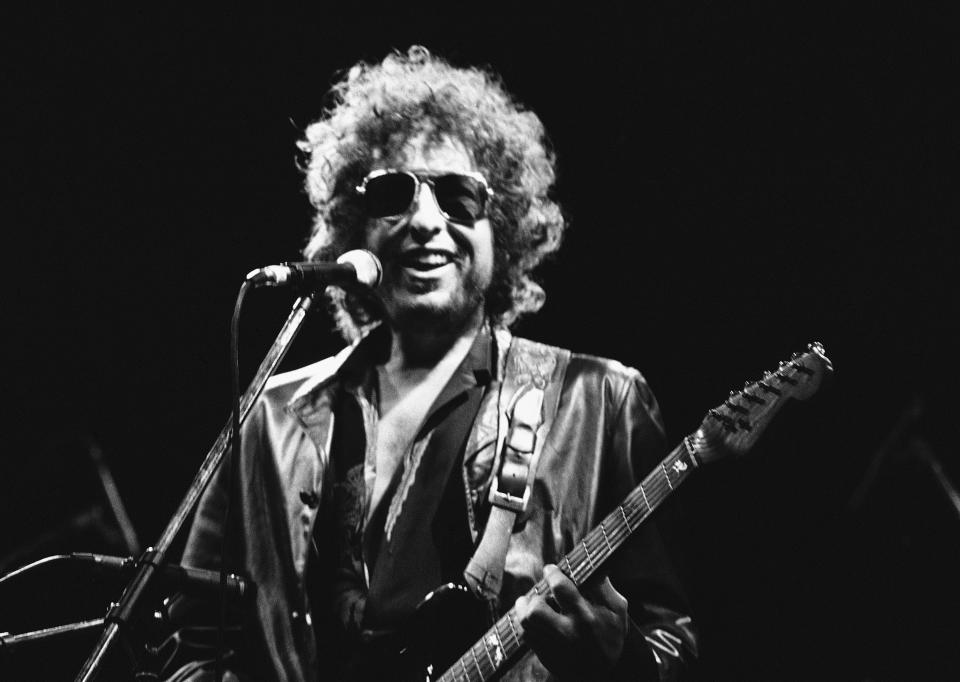 El músico estadounidense Bob Dylan sonríe durante un concierto en el estadio Colombes Olympic, en Colombes, Francia, el 24 de junio de 1981. El catálogo completo de canciones de Dylan, que abarca 60 años y está entre los más preciados, junto con el de los Beatles, fue adquirido por Universal Music Publishing Group en un acuerdo cuyos términos financieros no fueron revelados. (AP Foto/Herve Merliac, Archivo)