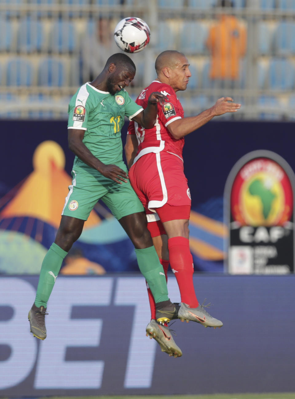 Senegal's Youssouf Sabaly, left, and Tunisia's Wahbi Khazri jump for the ball during the African Cup of Nations semifinal soccer match between Senegal and Tunisia in 30 June stadium in Cairo, Egypt, Sunday, July 14, 2019. (AP Photo/Hassan Ammar)