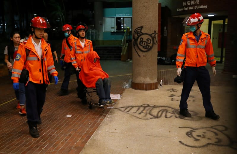 Paramedics escort a protester to an ambulance at the campus of the Polytechnic University (PolyU) in Hong Kong