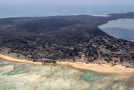 In this photo provided by the New Zealand Defense Force, volcanic ash covers roof tops and vegetation in an area of Tonga, Monday, Jan. 17, 2022. Thick ash on an airport runway was delaying aid deliveries to the Pacific island nation of Tonga, where significant damage was being reported days after a huge undersea volcanic eruption and tsunami. (CPL Vanessa Parker/NZDF via AP)