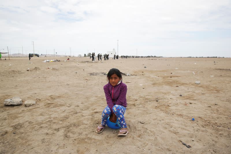 Una niña sentada mientras más atrás policías hacen guardia para evitar manifestaciones de trabajadores de empresas agroexportadoras sobre un acuerdo de reforma al sector y abordar sus quejas por malos salarios, en Villacuri, Perú