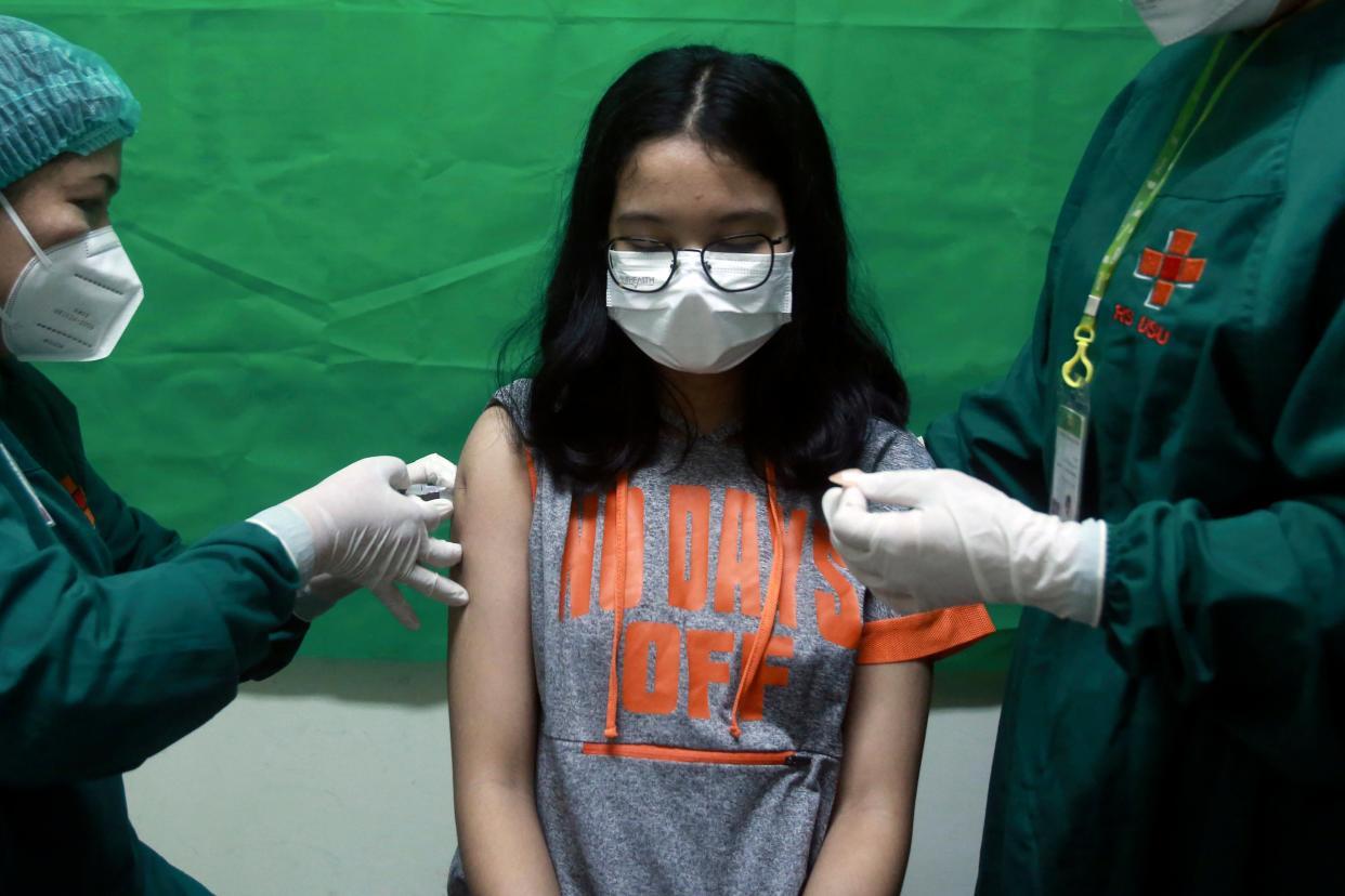 A young girl in Indonesia reacts as medical staff members give her a shot of the Sinovac COVID-19 vaccine during a vaccination campaign for children over twelve years of age (AP)