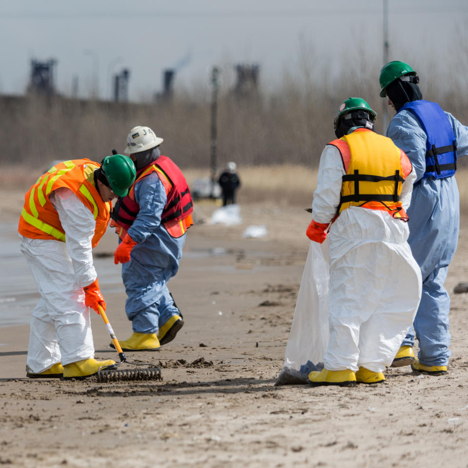 In this March 25, 2014 photo, workers comb the beach in Whiting, Ind. Crews for oil giant BP worked Tuesday to clean up an undetermined amount of crude oil that spilled into Lake Michigan and affected about a half-mile section of shoreline near Chicago following a malfunction at BP's northwestern Indiana refinery, officials said. (AP Photo/Sun-Times Media, Jim Karczewski) MANDATORY CREDIT, MAGS OUT, NO SALES