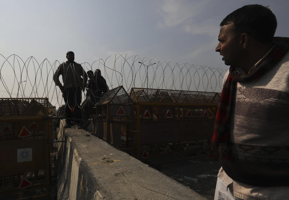 Workers put barbwires on top of barricades to stop protesting farmer entering the capital Delhi, at the Delhi-Uttar Pradesh border, on the outskirts of New Delhi, India, Saturday, Jan. 30, 2021. Indian farmers and their leaders spearheading more than two months of protests against new agriculture laws began a daylong hunger strike Saturday, directing their fury toward Prime Minister Narendra Modi and his government. Farmer leaders said the hunger strike, which coincides with the death anniversary of Indian independence leader Mahatma Gandhi, would reaffirm the peaceful nature of the protests. (AP Photo/Manish Swarup)