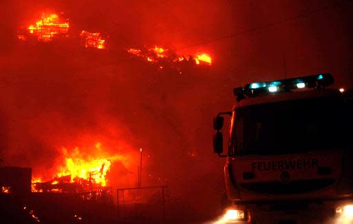 Un camión de bomberos presta apoyo cerca de casas en llamas durante un incendio en la ciudad portuaria de Valparaíso, 110 km al oeste de Santiago, Chile, el 12 de abril de 2014. (AFP | Felipe Gamboa)