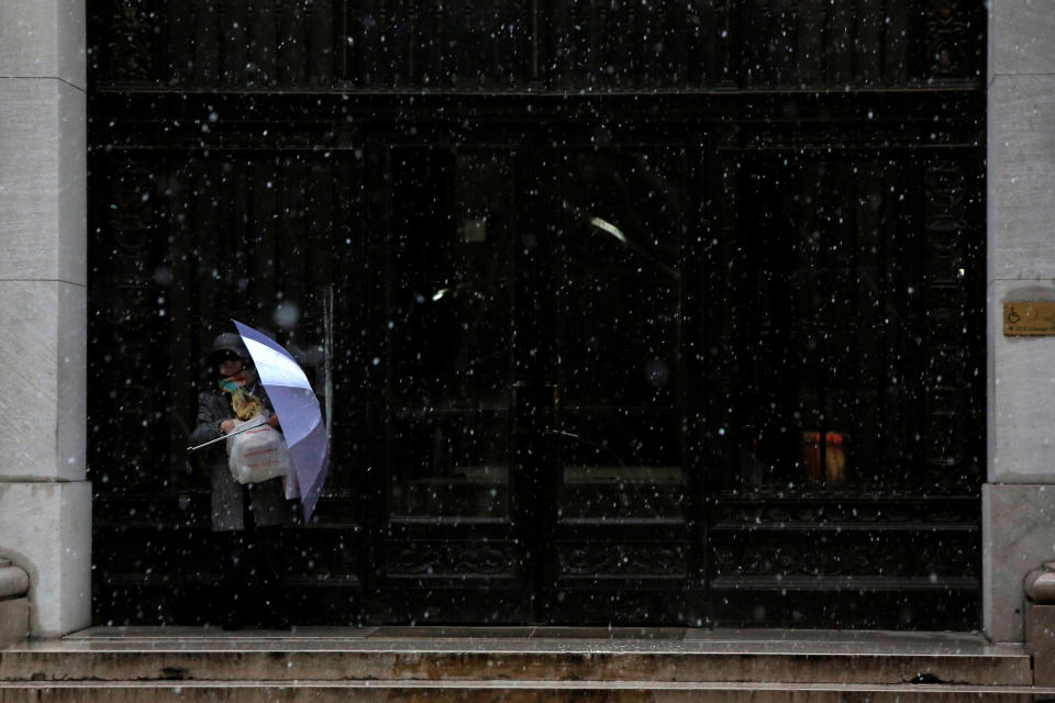 <p>A person finds cover in a doorway during the morning commute in the financial district during a winter nor’easter in New York City, March 2, 2018. (Photo: Andrew Kelly/Reuters) </p>