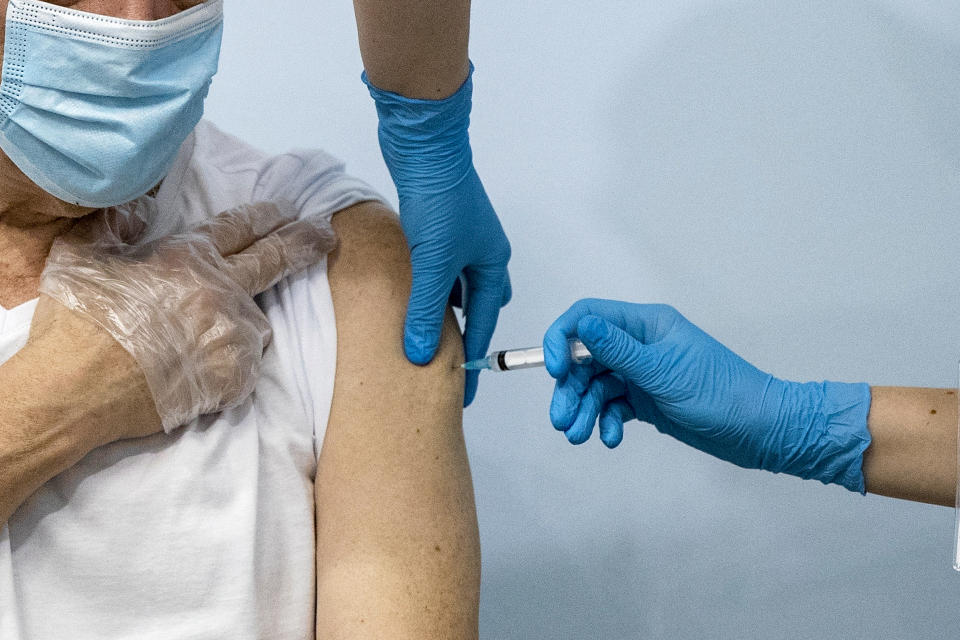 FILE - In this Jan. 20, 2021, file photo, a Russian medical worker, right, administers a shot of Russia's Sputnik V coronavirus vaccine to a patient in a vaccination center in Moscow, Russia. Authorities in four Russian regions this week made COVID-19 vaccinations mandatory for those working in certain sectors of the economy in a bid to boost Russia’s slow immunization rates as coronavirus infections continue to soar. Moscow was the first to announce the measure on Wednesday, June 16, 2021 and the surrounding Moscow region, the Siberian region of Kemerovo and the far eastern Sakhalin promptly followed suit. (AP Photo/Pavel Golovkin, File)