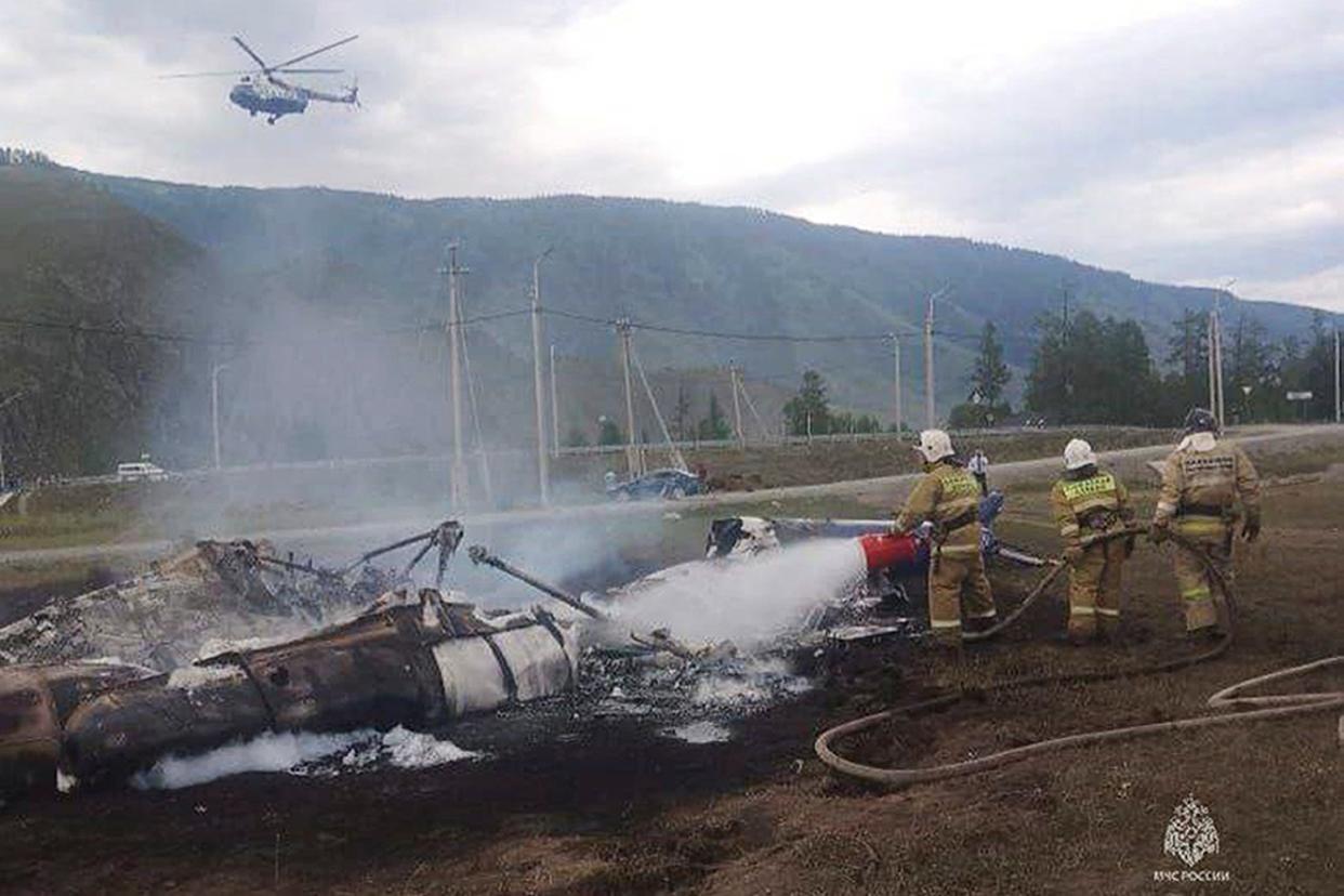 Firefighters extinguish a Mi-8 helicopter after the crash near Tyungur village, Altai Republic in southern Siberia, Russia (AP)
