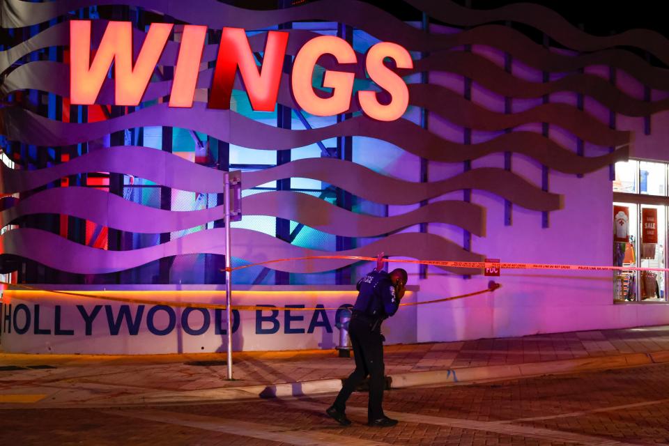 An officer passes through a crime scene tape cordon along a street as they respond to a shooting at Hollywood Beach on 29 May 2023 in Hollywood, Florida (Getty Images)