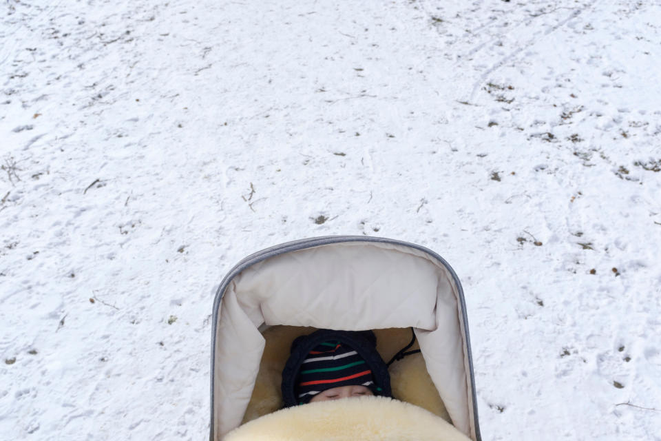 A baby sleeping in a stroller during winter.