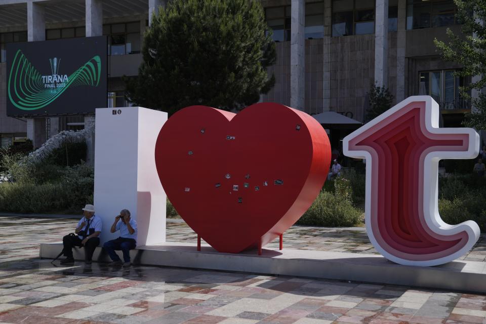 Two men sit in front of Opera building ahead of the Europa Conference League final between Roma and Feyenoord in Tirana, Albania, Wednesday, May 25, 2022. (AP Photo/Thanassis Stavrakis)