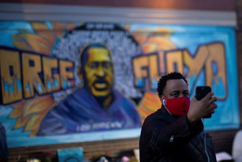 A local resident takes a selfie in front of a mural of George Floyd after the verdict in the trial of former Minneapolis police officer Derek Chauvin, found guilty of the death of George Floyd, at George Floyd Square in Minneapolis, Minnesota, U.S.