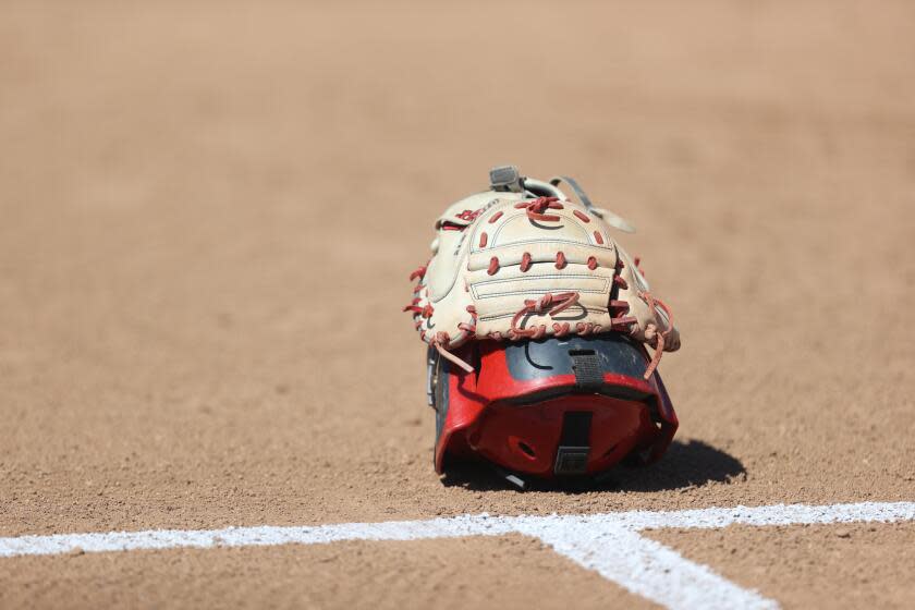 Softball catcher's helmet and glove on the field.