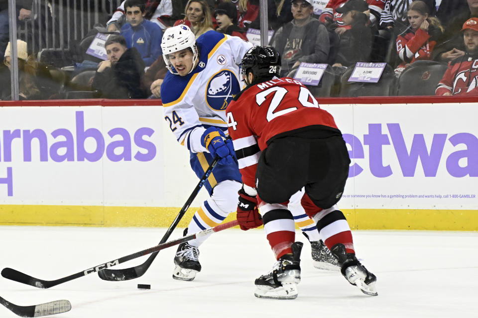 Buffalo Sabres center Dylan Cozens, left, passes the puck against New Jersey Devils defenseman Colin Miller, right, during the first period of an NHL hockey game Saturday, Nov. 25, 2023, in Newark, N.J. (AP Photo/Bill Kostroun)