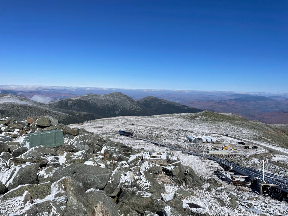 Wide view from the summit of a mountain with a train in the distance