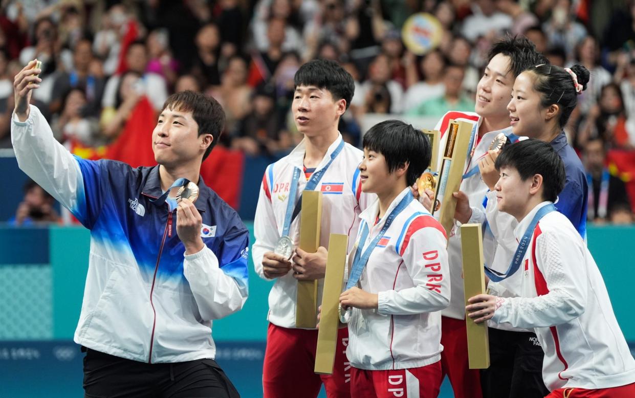 Silver medalists North Korea's Ri Jong Sik and Kim Kum Yong joins gold medalists China's Wang Chuqin and Sun Yingsha, and  bronze medalists South Korea's Lim Jonghoon and Shin Yubin on the table tennis podium at the Paris Olympics