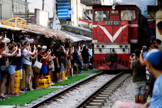 Visitors and tourists stand on the sides of a railway track to photograph a passing train in Hanoi, June 9, 2019.<span class="copyright">Manan Vatsyayana—AFP via Getty Images</span>