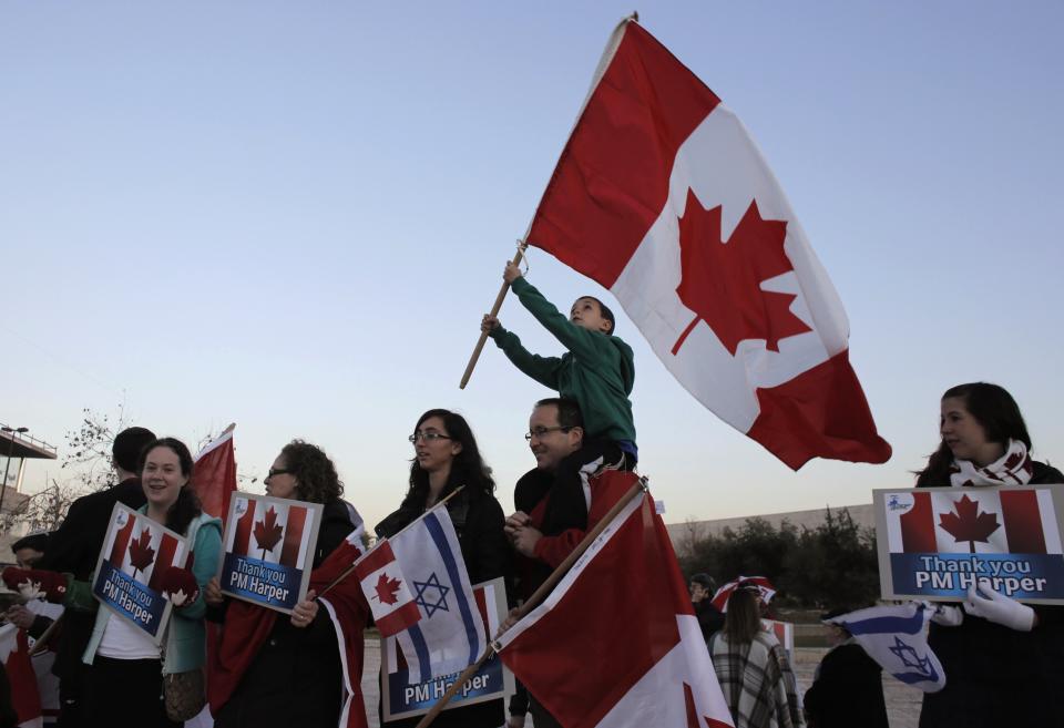 Israelis hold signs and Canadian flags during a rally to thank Canada's Prime Minister Stephen Harper for his support of Israel during his visit at the Israeli parliament in Jerusalem January 20, 2014. REUTERS/Ammar Awad (JERUSALEM - Tags: POLITICS)