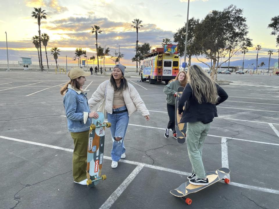 Hannah Dooling, from left, Jane Kang, Christie Goodman, and Yun Huang gather in a vacant parking lot to practice longboarding in Santa Monica, Calif., on Feb. 26, 2023. Longboard dancing is still in its infancy. But fans say the skate/dance hybrid has already spread in southern California, Paris, Seoul and other places with public squares or wide, open sidewalks. (Kristina Garcia Wade via AP)