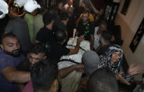 Mourners gather around a covered dead body, one of several victims who were on a boat carrying migrants from Lebanon that sank in Syrian waters, in Tripoli, north Lebanon, Sept. 23, 2022. Syria's health minister says several people have been killed from a boat that sank migrants from Lebanon off Syria's coast. The incident is the deadliest since a surging number of Lebanese, Syrians, and Palestinians have tried to flee crisis-hit Lebanon by sea to Europe. (AP Photo/Bilal Hussein)