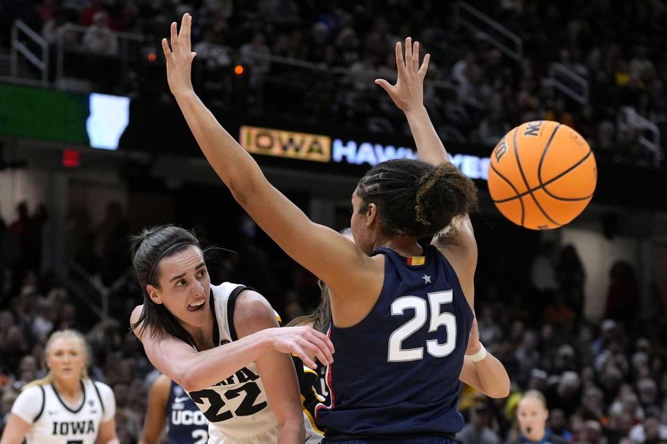 Iowa guard Caitlin Clark (22) passes around UConn forward Ice Brady (25) during the second half of a Final Four college basketball game in the women's NCAA Tournament, Friday, April 5, 2024, in Cleveland. (AP Photo/Morry Gash)