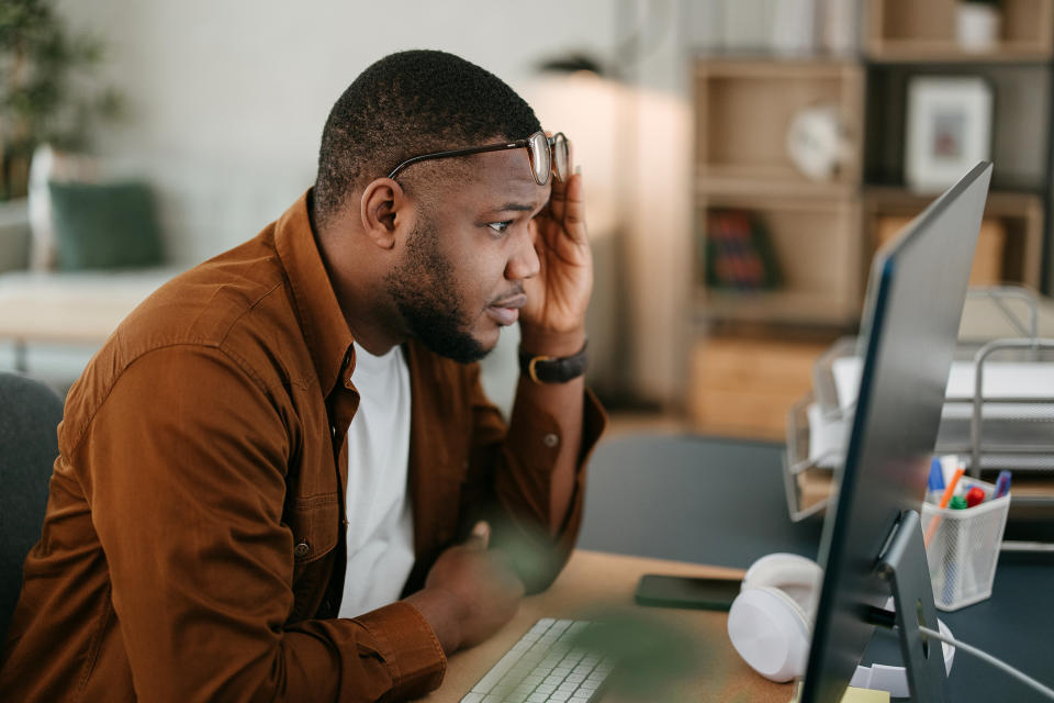 Man in a brown shirt working intently at a computer in an office setting