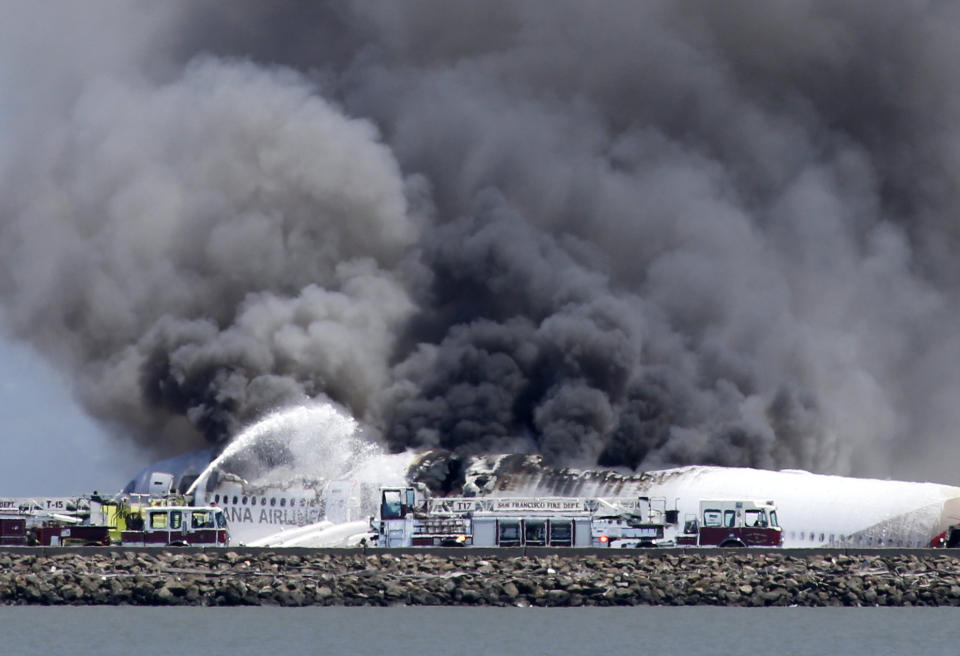 Fire crews work the crash site of Asiana Flight 214 at San Francisco International Airport in San Francisco, Saturday, July 6, 2013. (AP Photo/Bay Area News Group, John Green)