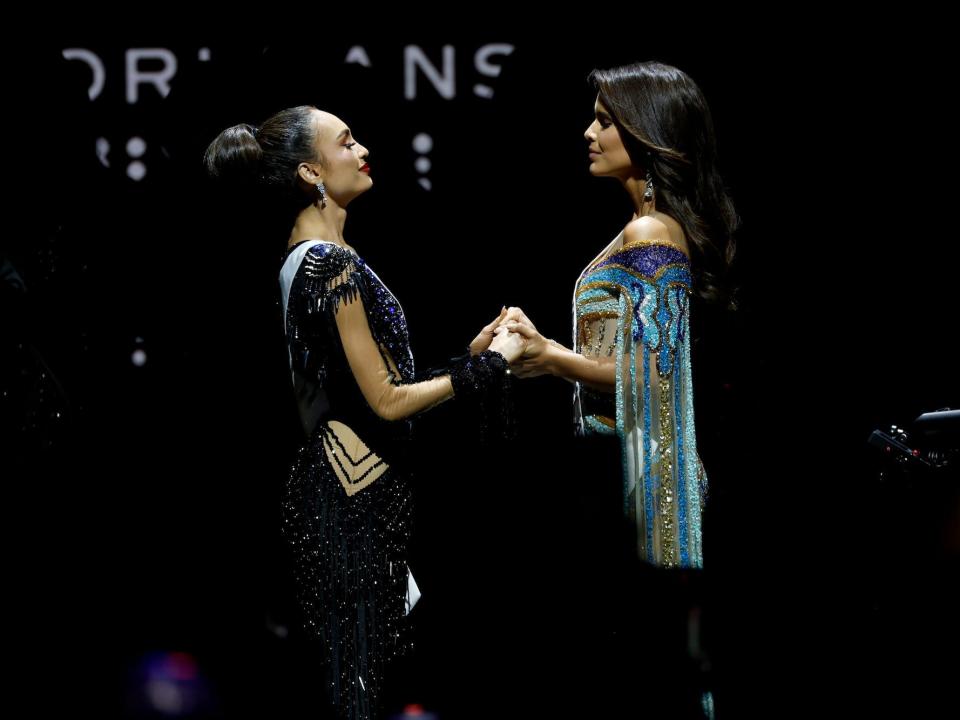 Miss USA and Miss Venezuela hold hands during the 71st annual Miss Universe pageant.