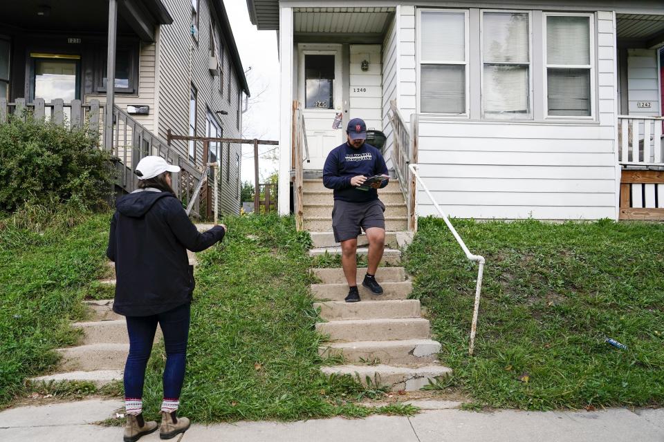 Los activistas Diego Rebollar y Andreina Patilliet van de puerta en puerta haciendo proselitismo para los republicanos en el south side de Milwaukee el 8 de octubre del 2022. (AP Photo/Morry Gash)